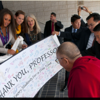 His Holiness the Dalai Lama is presented with a card signed by students during a break in the