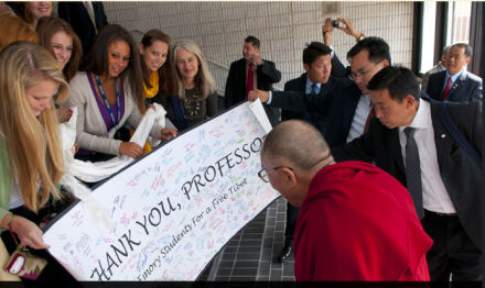 His Holiness the Dalai Lama is presented with a card signed by students during a break in the